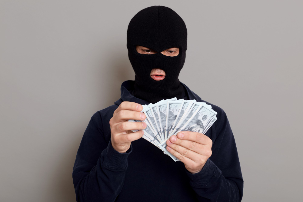 robber man dressed black hoodie stands with disguised face holds lot money his hands