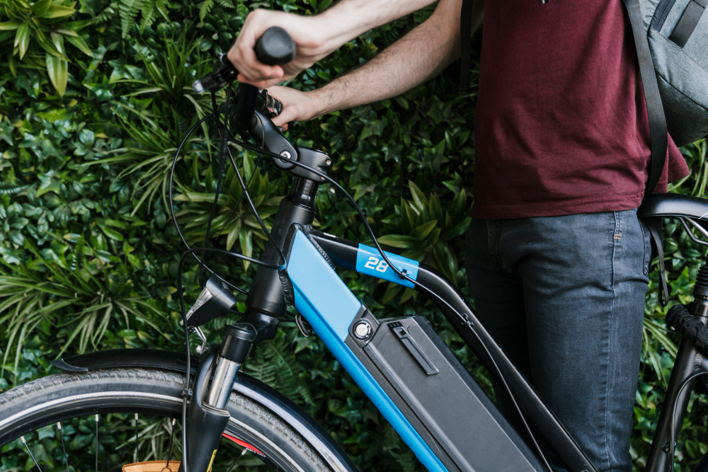 close up sideways cyclist holding e bike with green wall background