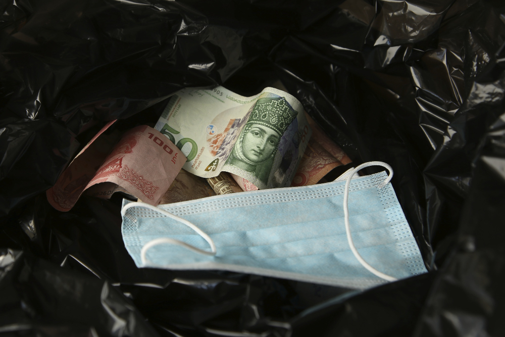 money from around world face mask inside black plastic trash bag