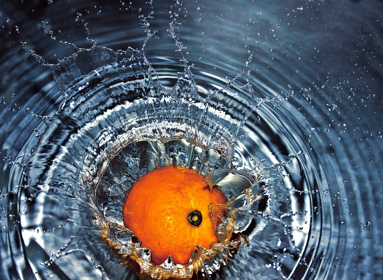 Pomaranča, ki pade v vodo. Umivanje sadja in zelenjave