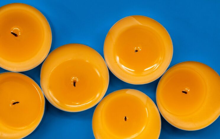 Oranžne dišeče sveče na modri podlagi, ki lahko negativno vplivajo na zdravje.
