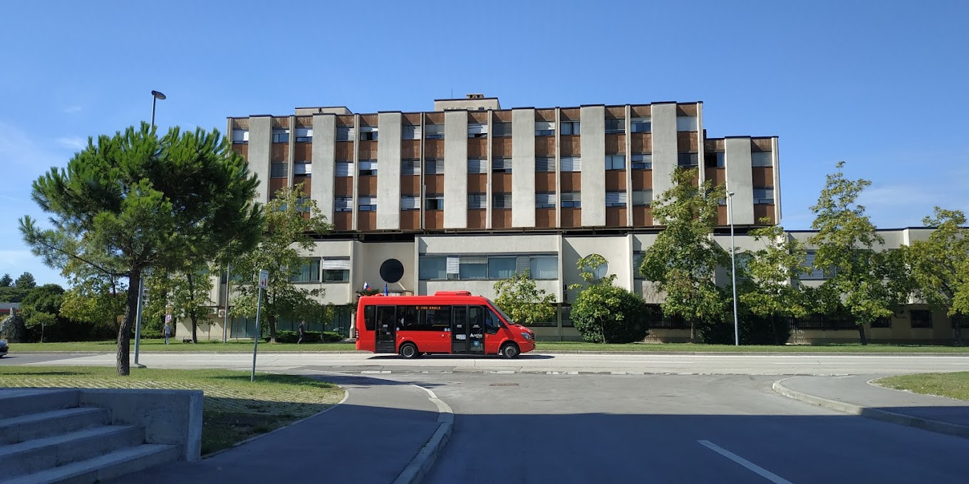 Rdeč avtobus, ki je prekiran pred stanovanjskim naseljem.