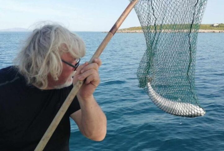 ribič z mrežo in ribo v mreži