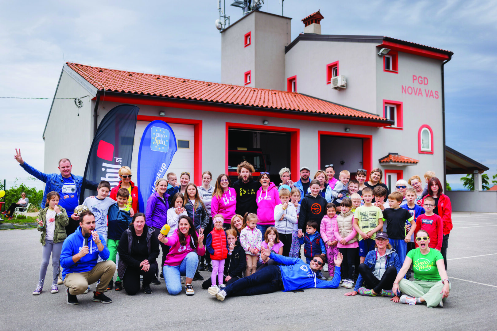 Skupina otrok in odraslih pred gasilnim domom