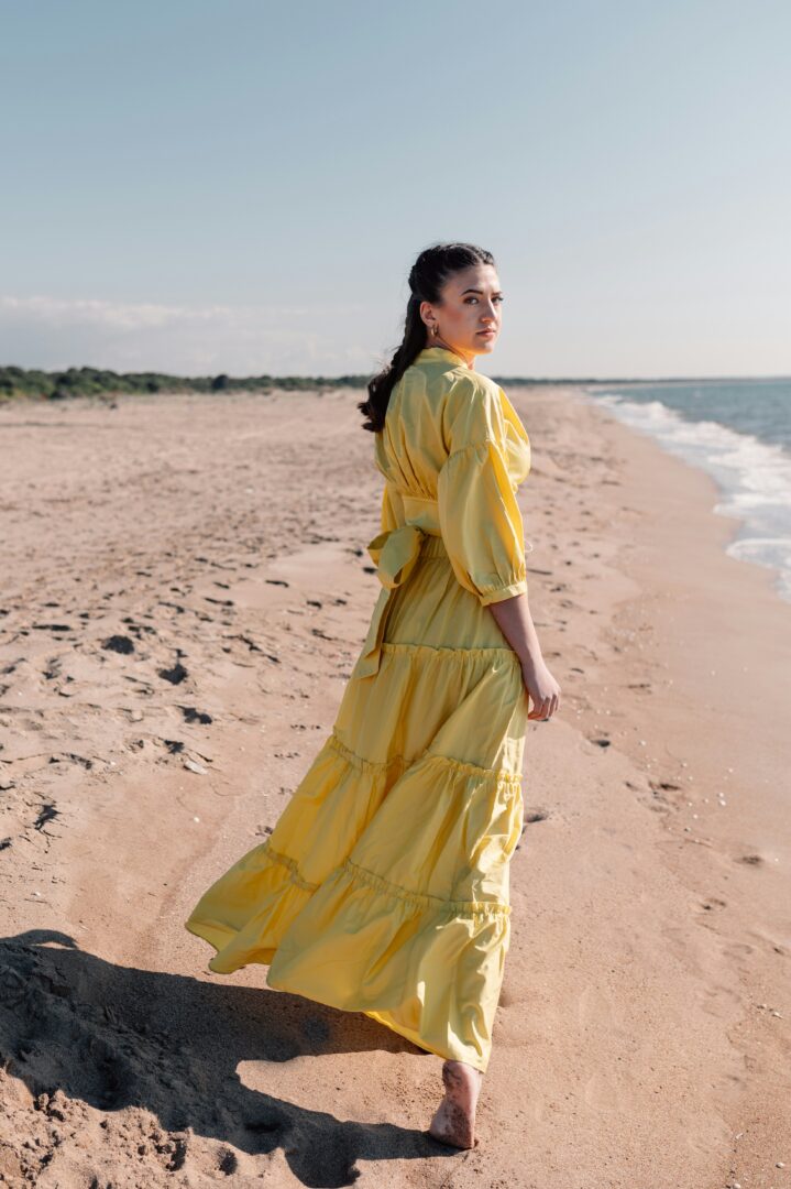 ženska v dolgi rumeni obleki na peščeni obali