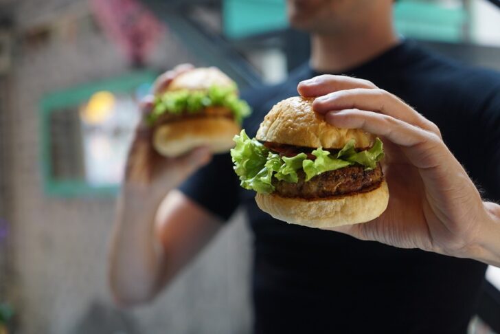 hrane hamburgerji moški drži dva hamburgeja